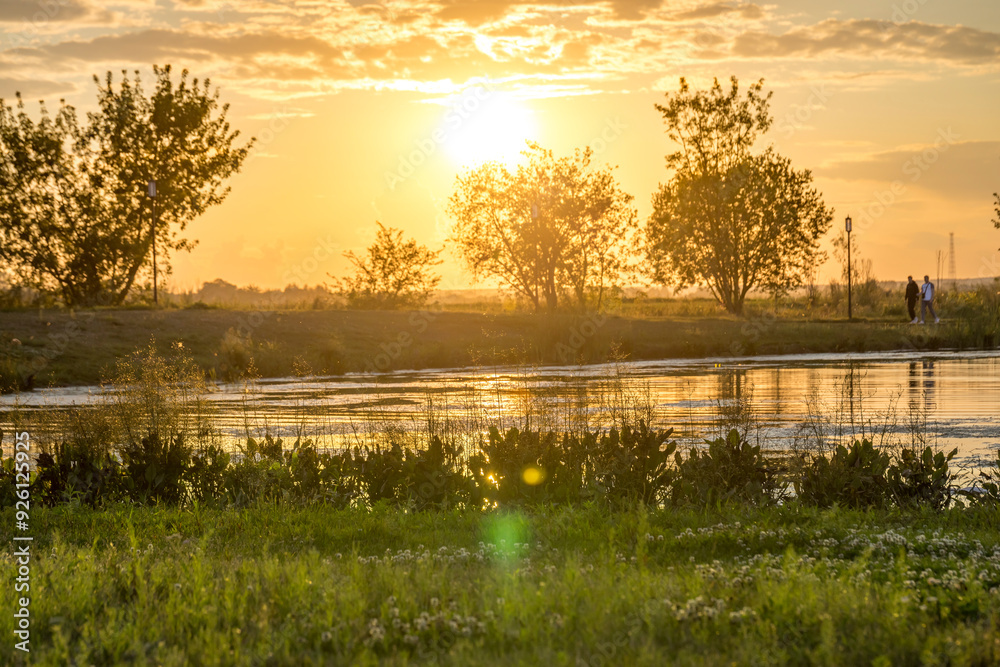 Obraz premium A beautiful sunset over a lake with trees in the background