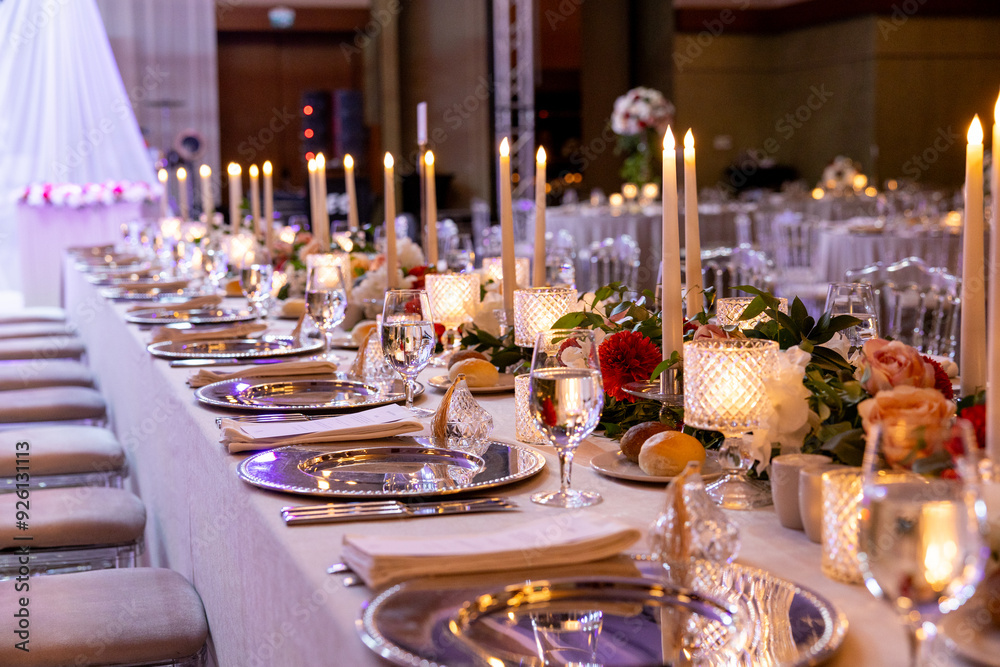 Long and elegant wedding table with candles and floral centerpiece Long and elegant wedding table with candles and floral centerpiece