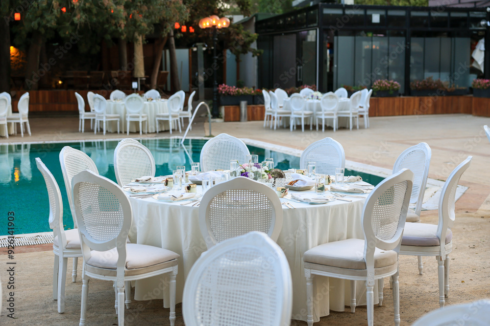 Elegant Poolside Wedding Reception with Round Tables and White Chairs