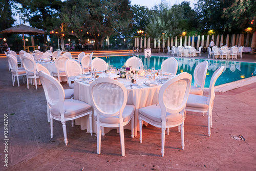 Outdoor Wedding Setup: Round Tables and Floral Decor by a Swimming Pool