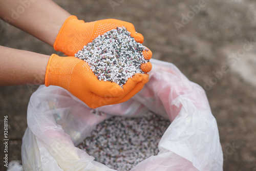 Close up hands hold mixed chemical fertilizer. Concept; chemical fertilizer production use in agriculture consists of basic nutrients which are Nitrogen (AND), Phosphate (P2O5) and Potassium (K2O).   