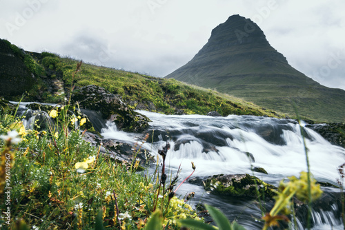 Kirkjufell mit einem Fluss im Vordergrund und unscharfen Kräutern mit Wassertropfen vom Regen photo