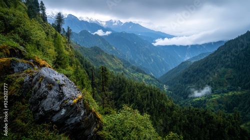  A panorama of mountain ranges, their peaks adorned with green foliage, distant vistas of mountains, clouds drifting in the blue sky, and fog gently enveloping