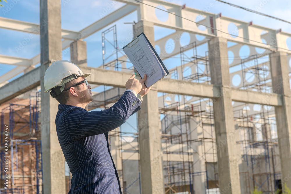 Asian adult foreman stands in front of the construction inspecting a construction project with determination. Engineer inspects construction. Asian adult foreman stands in front of the construction inspecting a construction project with determination. Engineer inspects construction.