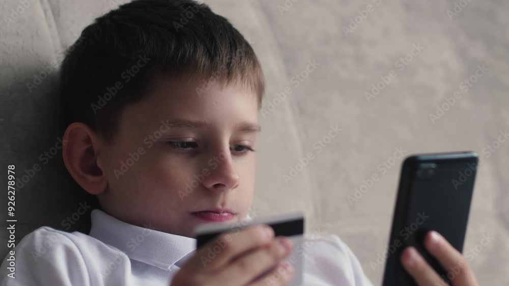 teenager shopping online, caucasian boy 11 years old shopping online sitting on couch at home holding bank card and phone teenager shopping online, caucasian boy 11 years old shopping online sitting on couch at home holding bank card and phone