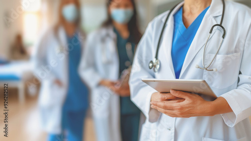 A doctor is holding a tablet in front of three other doctors.