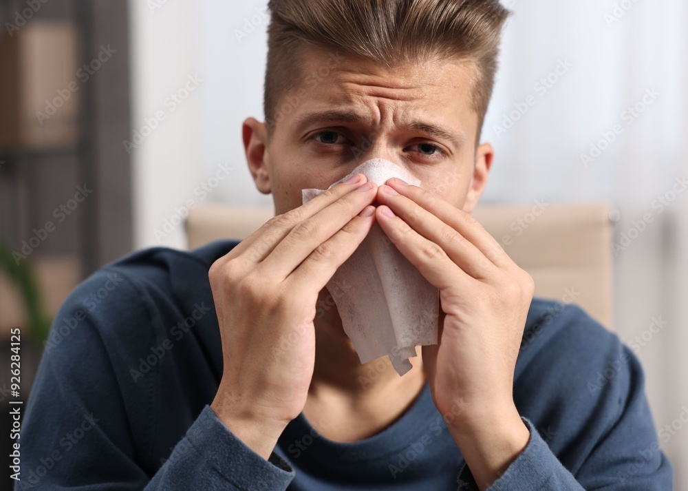 Young man with tissue suffering from sinusitis indoors Young man with tissue suffering from sinusitis indoors
