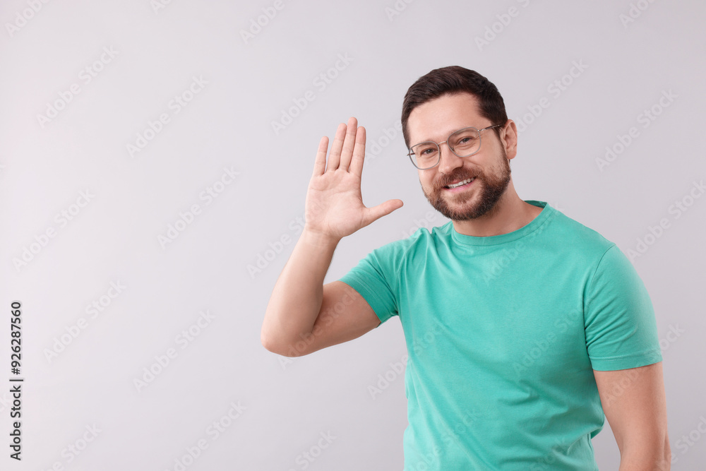 Cheerful man waving on light background. Space for text Cheerful man waving on light background. Space for text
