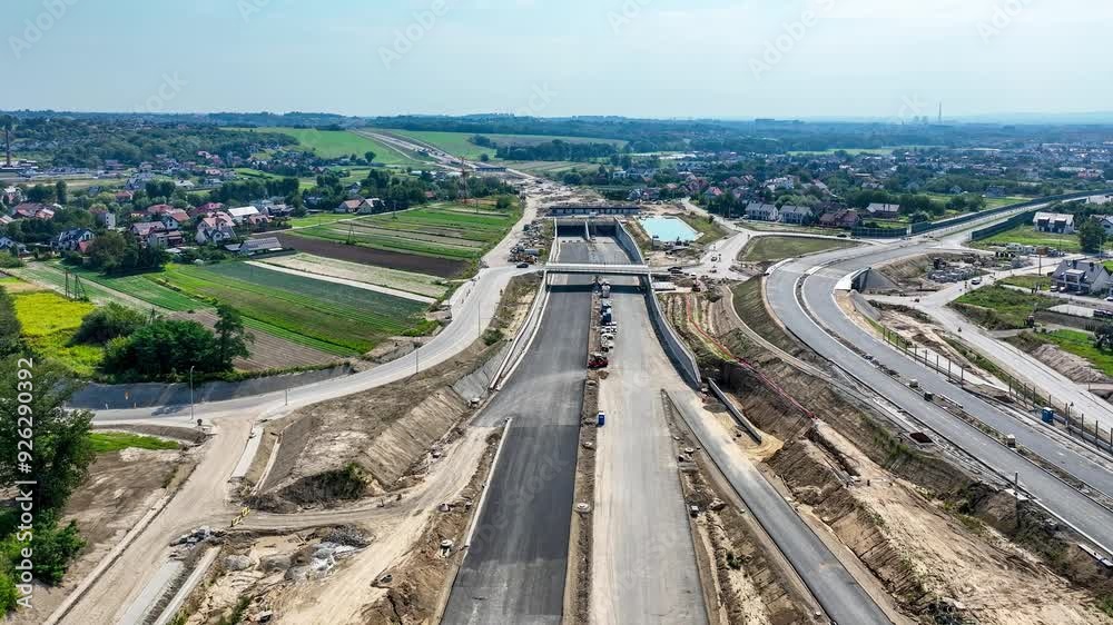 Northern part of highway bypass around Krakow under construction. Fragment S52 with Zielonki junction with traffic circle, tunnel, viaducts and ramps. State in August 2024. Aerial 4K revealing video Northern part of highway bypass around Krakow under construction. Fragment S52 with Zielonki junction with traffic circle, tunnel, viaducts and ramps. State in August 2024. Aerial 4K revealing video