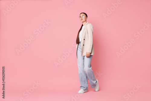 Stylish woman in beige jacket and jeans on pink background