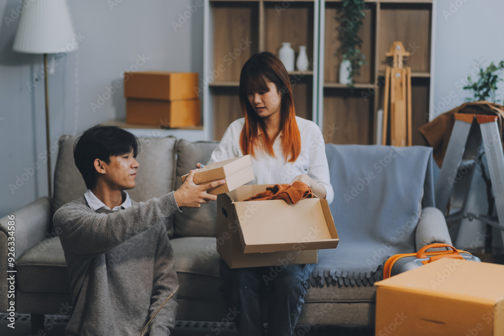 Young Asian couple relocating to a new house, joyfully packing and unpacking belongings. Expertise in moving, packing, togetherness, and creating a new home together. Young Asian couple relocating to a new house, joyfully packing and unpacking belongings. Expertise in moving, packing, togetherness, and creating a new home together.
