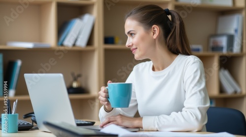 A young woman at her desk gazes thoughtfully into the distance, taking a break from work on her laptop, surrounded by books and office supplies. Free Download A young woman at her desk gazes thoughtfully into the distance, taking a break from work on her laptop, surrounded by books and office supplies. - GFXLoad