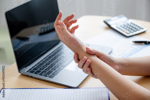 A successful business woman sitting in the office Using a laptop to work so hard that it hurts her wrists