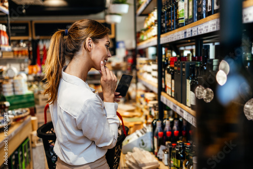 Fotografija Beautiful young and elegant woman buying some healthy food and drink in modern supermarket or grocery store