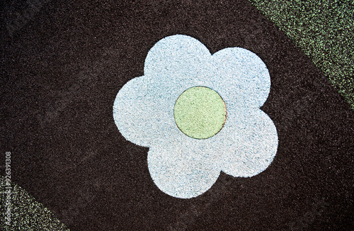 Playground floor rubber play park with a flower. Black and green rubber ground. Top view. Close up.