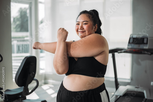 Plus size Asian woman exercises in gym. Beautiful overweight woman in sportswear smiling and happy in fitness. concept of body positive, self-acceptance, weight loss.