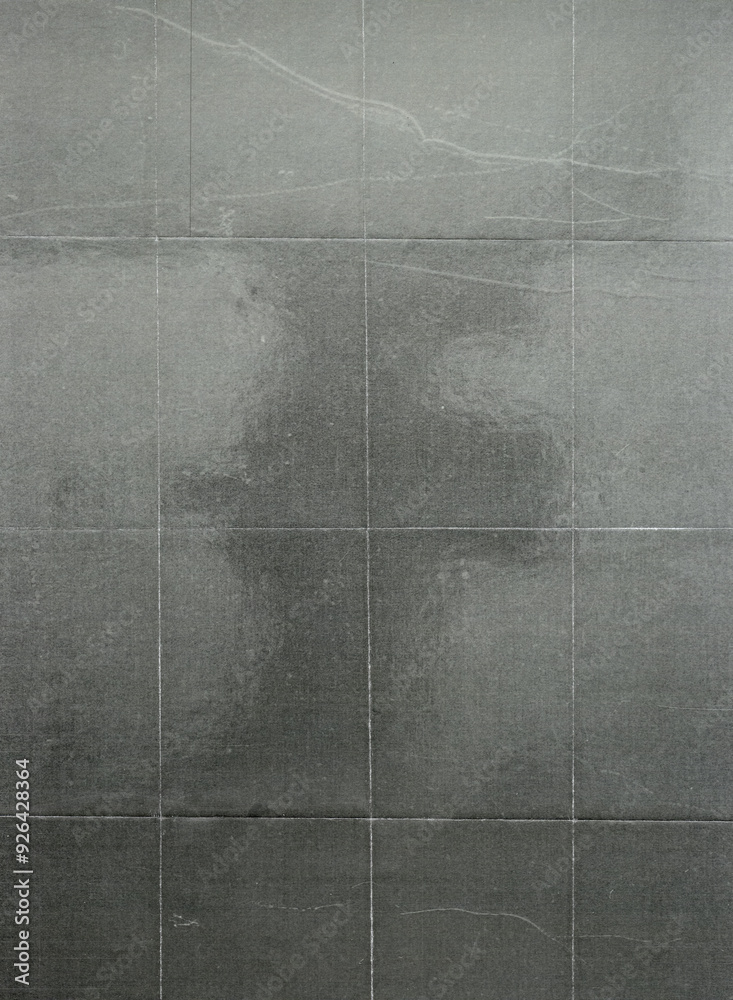 Fototapeta premium A sheet of crumpled paper with a gray tone, reflecting the texture and quality of an old-fashioned photograph. The background is dark gray to enhance its classic feel. 