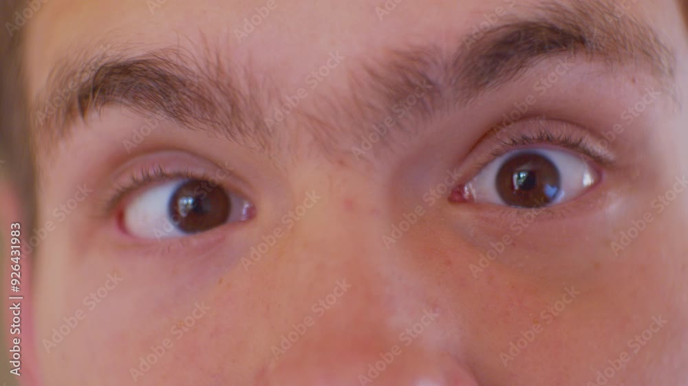 A surprised teenager looks at the camera with big bulging eyes. Eyes of a surprised or frightened person. Face of a modern person. Close-up. Shallow depth of field. A surprised teenager looks at the camera with big bulging eyes. Eyes of a surprised or frightened person. Face of a modern person. Close-up. Shallow depth of field.