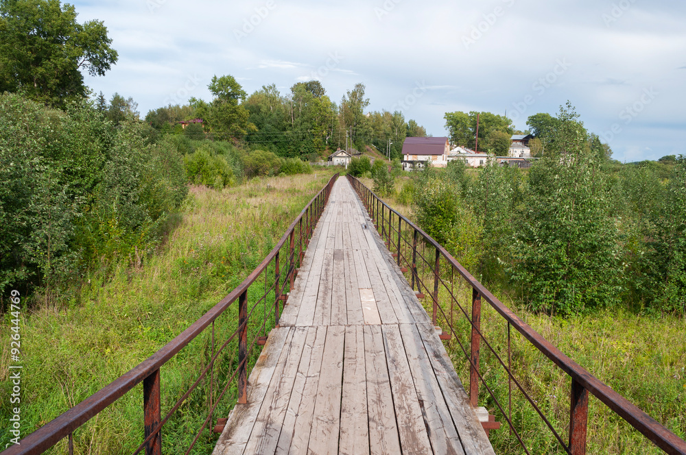 Long wooden pedestrian bridge with iron railings, Totma, Vologda region, Russia Long wooden pedestrian bridge with iron railings, Totma, Vologda region, Russia