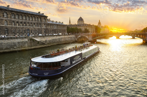The Seine River in Paris with a historic bridge and the illuminated Eiffel Tower in the background. The calm water reflects the city lights, creating a romantic atmosphere of a Parisian evening