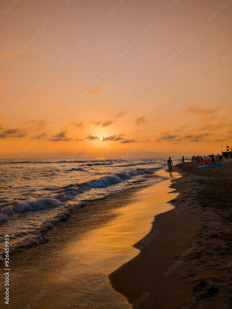 Golden sunset over a peaceful beach with gentle waves and a person walking along the shoreline, creating a tranquil and serene atmosphere. Golden sunset over a peaceful beach with gentle waves and a person walking along the shoreline, creating a tranquil and serene atmosphere.