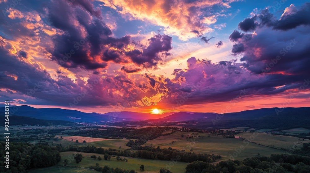 Fototapeta premium Amazing sunset with dramatic clouds illuminated in fiery colors above a peaceful rural landscape.