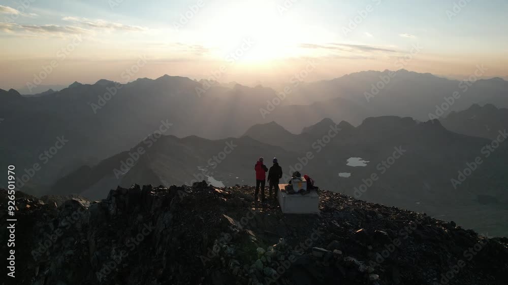 Dos personas alpinistas en la cima de una montaña en el amanecer o atardecer