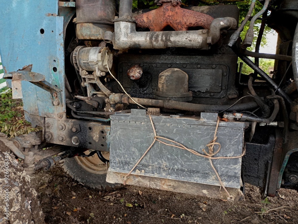 The engine compartment of an old tractor with a battery motor and an exhaust gas exhaust system. Agricultural machinery background and metal tractor structure. The engine compartment of an old tractor with a battery motor and an exhaust gas exhaust system. Agricultural machinery background and metal tractor structure.