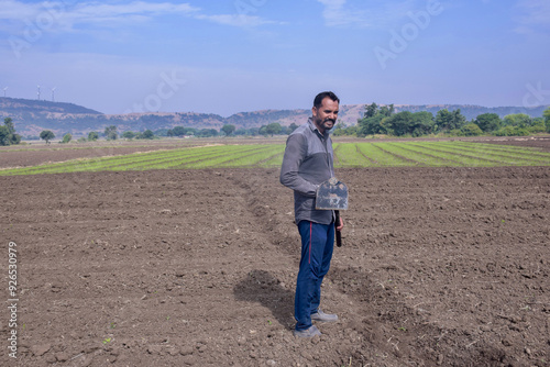 Indian farmer digging his field with a spade, farm and sky background