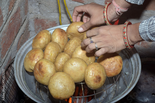 Indian housewife's hands baking on Bati oven, close-up of Rajasthani Indian dish, wheat flour balls, kitchen background. traditional unleavened bread photo