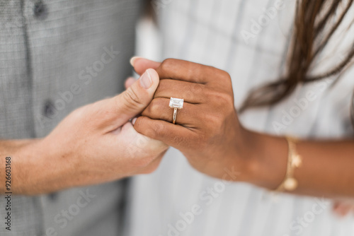 woman and man holding hands while displaying their proposal diamond ring 