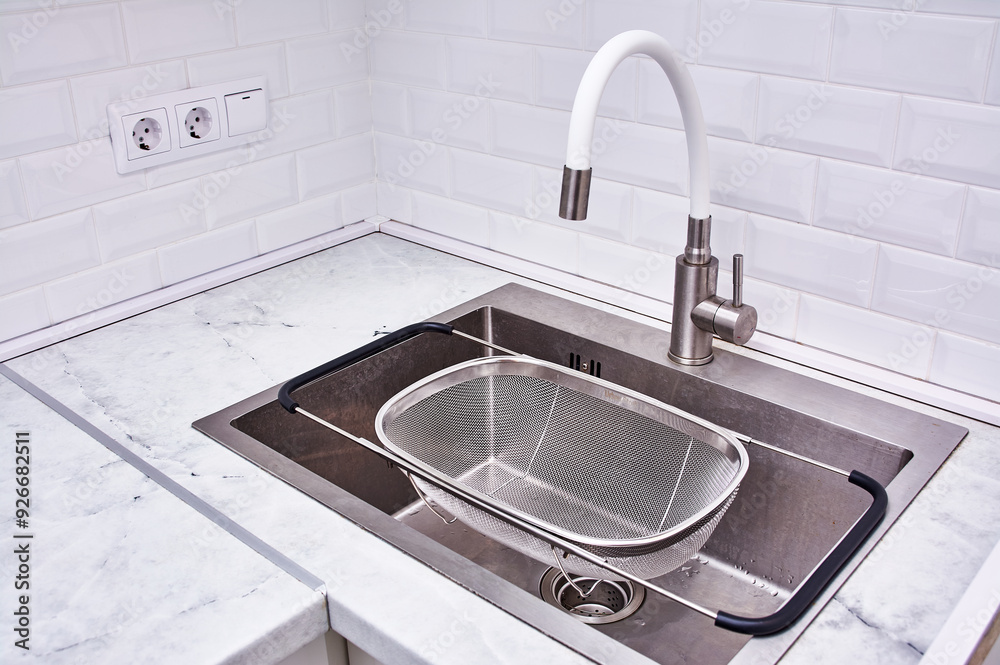 A silver sink with a mesh strainer in it A silver sink with a mesh strainer in it