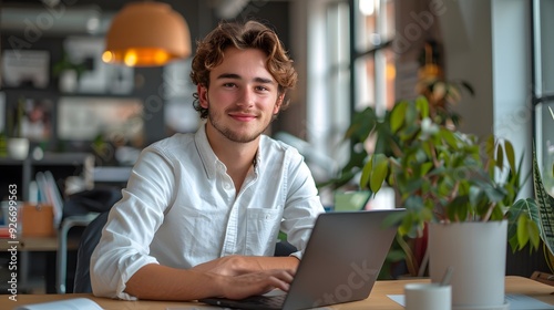 Portrait of young man working on laptop computer at modern office.