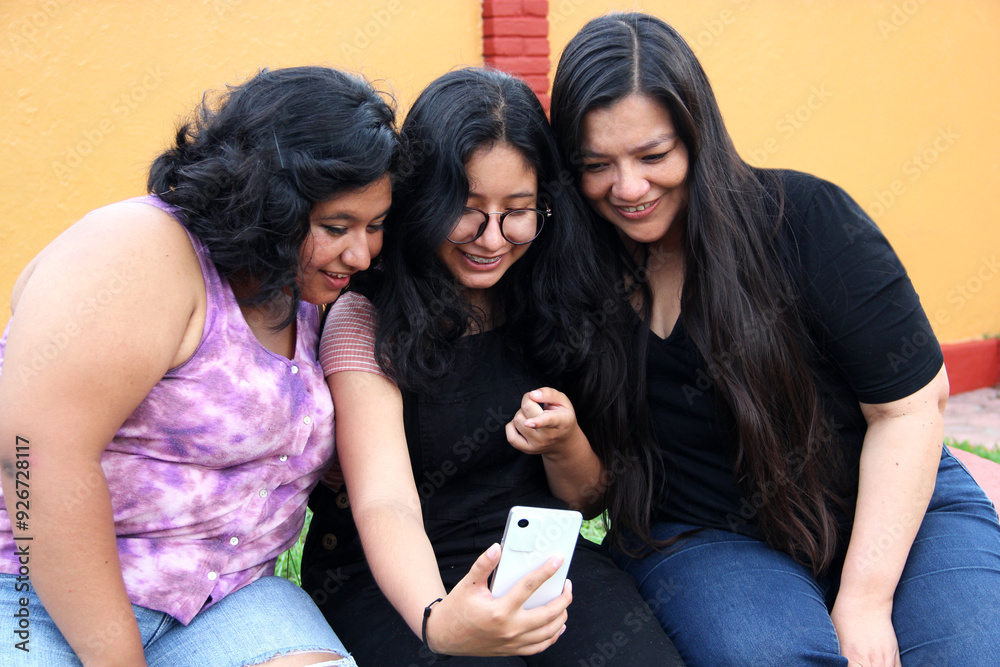 Three brunette Latin women use cell phones to make video calls and take selfie photos, enjoy and spend quality time