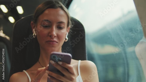 Young woman with headphones use phone in train