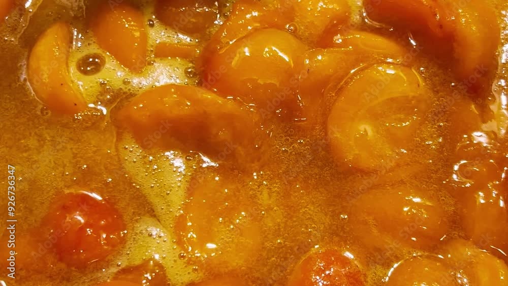 The process of making apricot jam in a metal pan. The jam is cooked in a pan. The process of making apricot jam in a metal pan. The jam is cooked in a pan.
