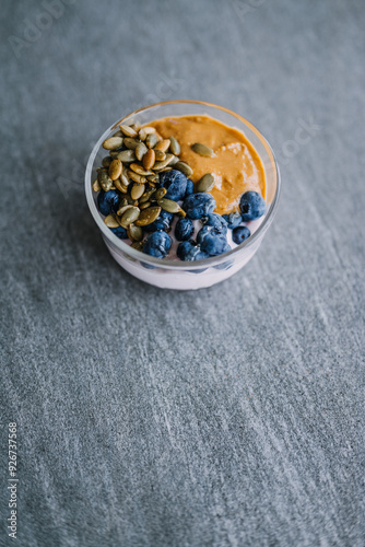 blueberries in a glass bowl with pumpkin seeds and peanut butter drizzled with honey