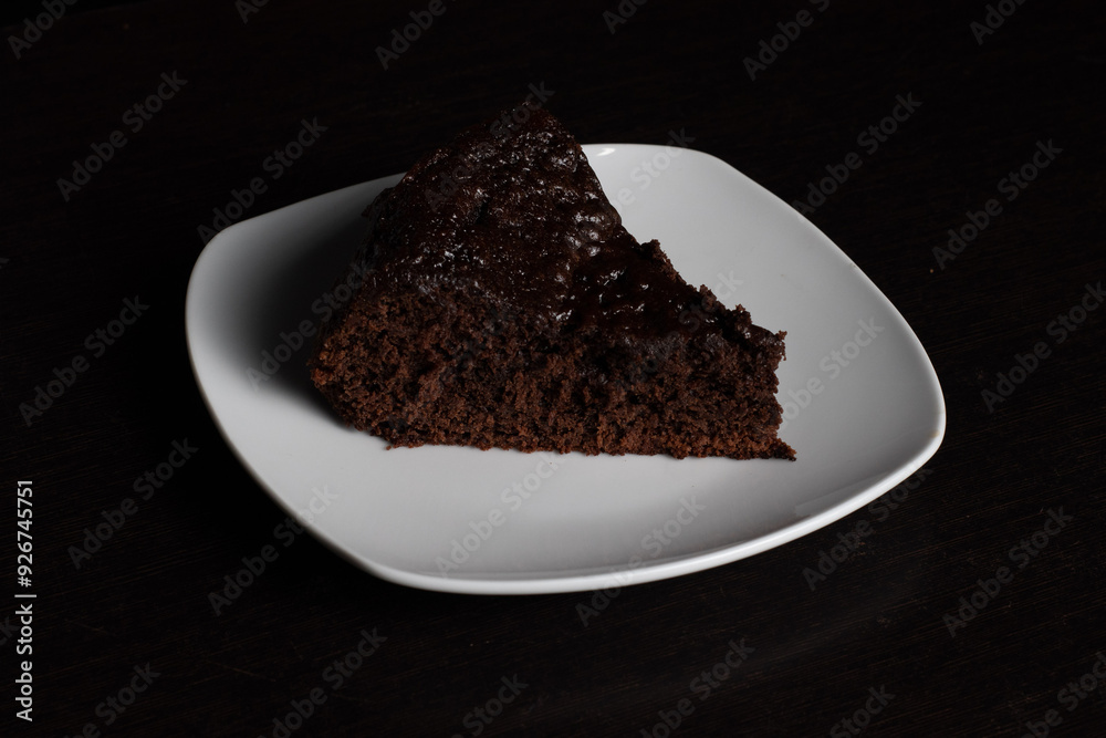 Chocolate Cake Slice on White Plate with Black Background Chocolate Cake Slice on White Plate with Black Background