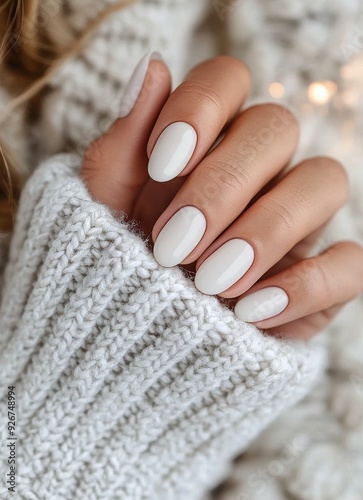 Elegant white nail design showcased with a cozy knitted sweater in a warm ind...