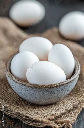 Fresh white eggs in a rustic bowl on burlap fabric