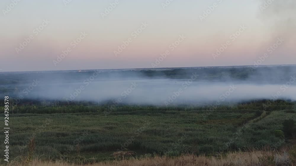 Smoke from a fire over fields and valley in the evening Smoke from a fire over fields and valley in the evening