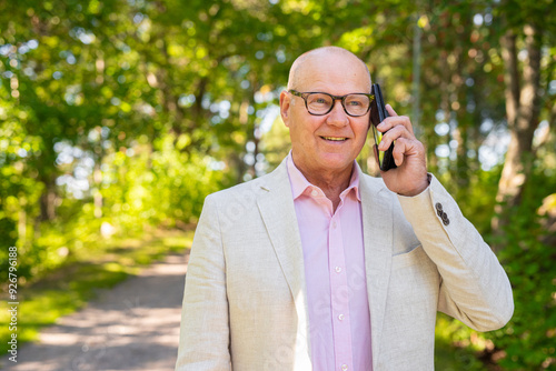 Happy Scandinavian Senior Man Using Phone Outdoors in Summer Joyful Technology Use