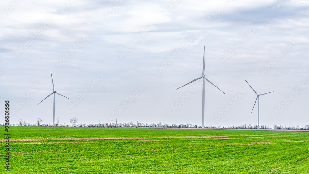 Wind turbines generating electricity in a green field. Green power generation concept. Wind turbines generating electricity in a green field. Green power generation concept.