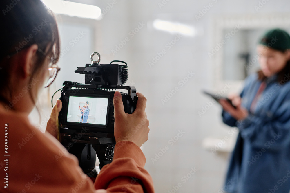 Photographer using professional camera equipment while directing subject in blurry background for photoshoot in indoor setting Photographer using professional camera equipment while directing subject in blurry background for photoshoot in indoor setting