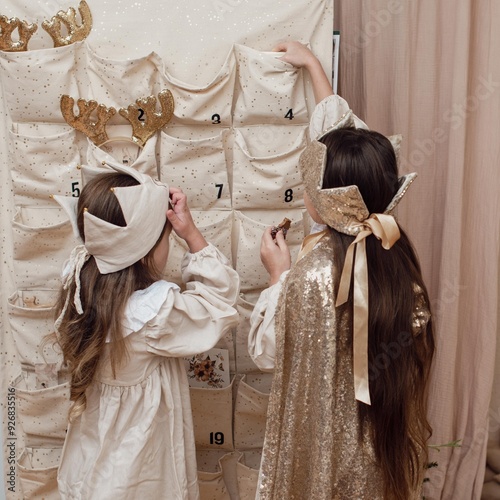 Little happy child opening first day in handmade advent calendar made from toilet paper rolls.