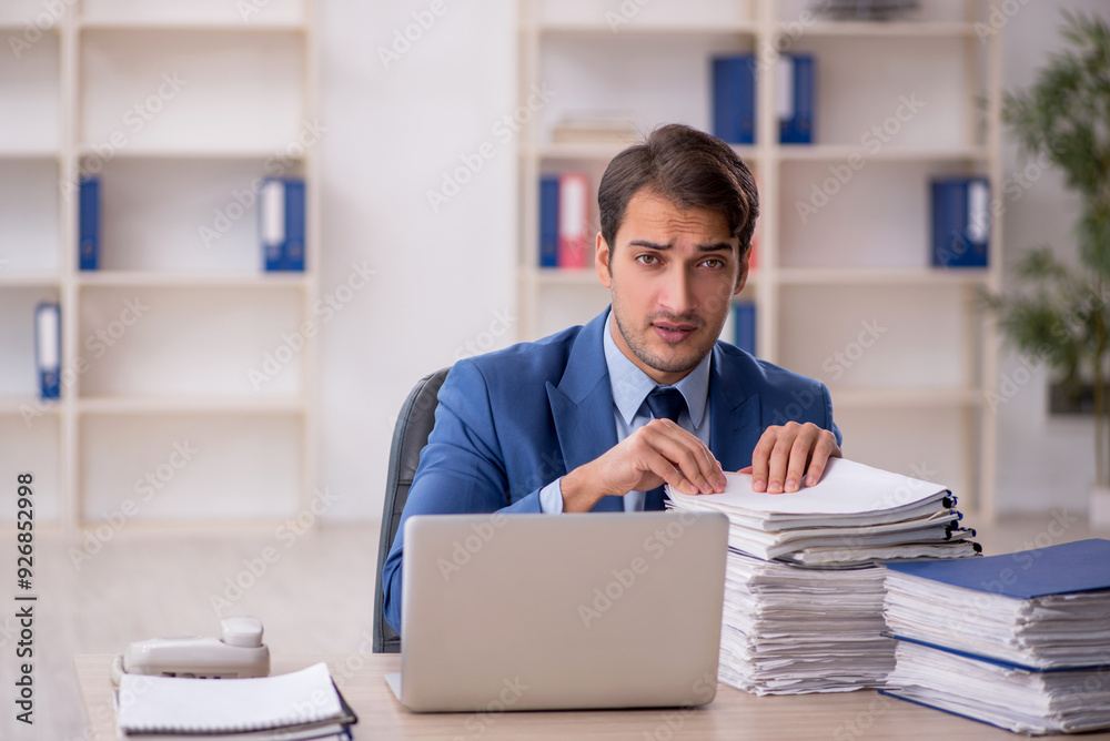 Young male employee and too much work in the office Young male employee and too much work in the office