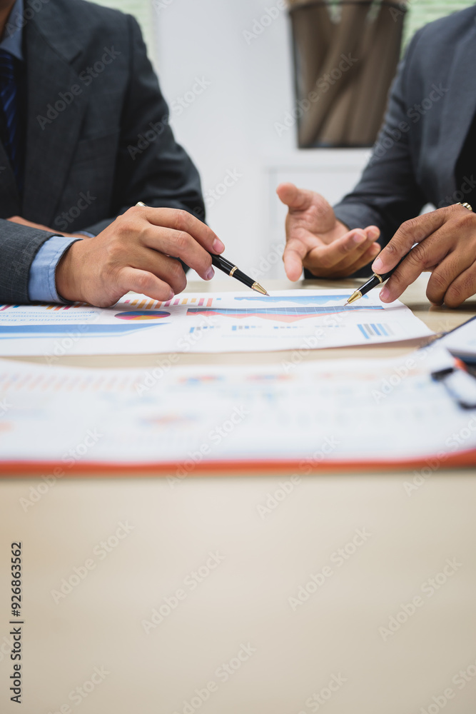 Asian business team engages in a collaborative meeting, financial charts at a desk. Dressed in formal suits, they brainstorm creative ideas to enhance company performance and team cohesion. Asian business team engages in a collaborative meeting, financial charts at a desk. Dressed in formal suits, they brainstorm creative ideas to enhance company performance and team cohesion.