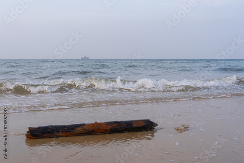 log lying on the beach, clear wave patterns, aquaculture facility in the sea photo