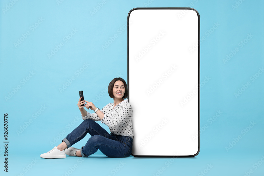 Φωτογραφία Beautiful young woman with smartphone sitting near big mobile phone with blank s