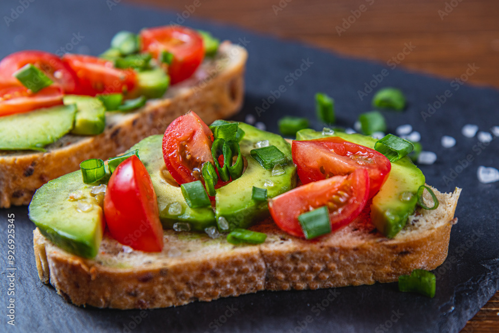 Avocado toast topped with tomato and green onion on a slice of carrot bread Avocado toast topped with tomato and green onion on a slice of carrot bread